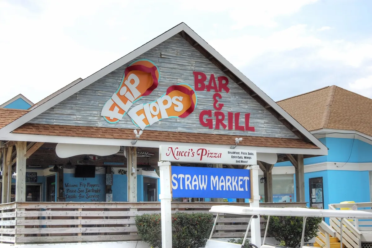 This scene features the Flip Flops Bar & Grill and Nucci's Pizzeria signs, with outdoor seating areas, casual diners, and a laid-back open-air market vibe, all hinting at the variety of places to eat, drink, and unwind with friends.