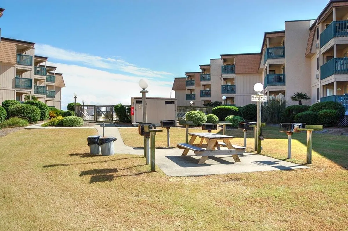 A landscaped exterior area featuring picnic tables and grill stations, ideal for barbecuing, picnicking, and hosting family gatherings. The relaxed atmosphere and open layout suggest a space where large groups can dine together and create memories outdoors.