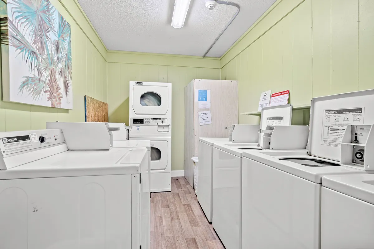 A practical, well-maintained laundry room with washing machines, dryers, and cheerful artwork on the wall, creating a functional yet inviting environment for residents.