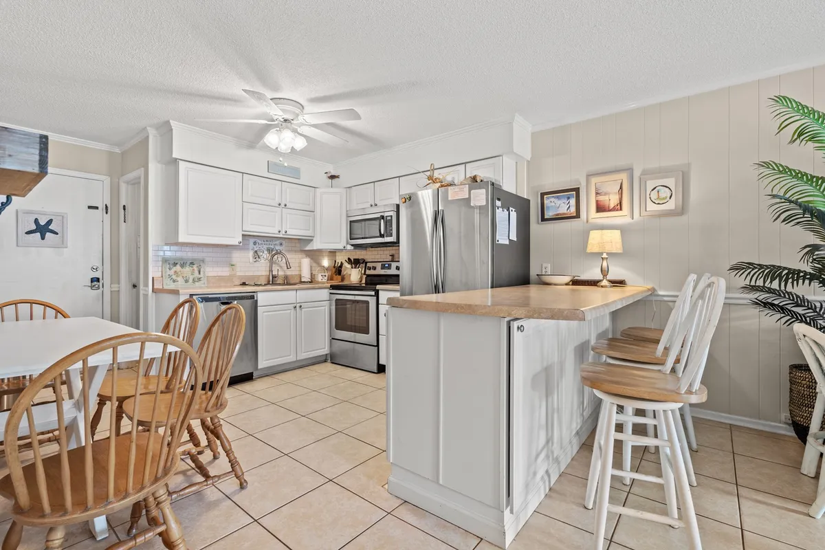 This image showcases a welcoming, well-lit kitchen and dining area, featuring a spacious kitchen island, modern appliances, a dining table set for meals, and tasteful decorative elements on the walls. The space feels inviting and ideal for family meals, entertaining, or relaxing with coffee.