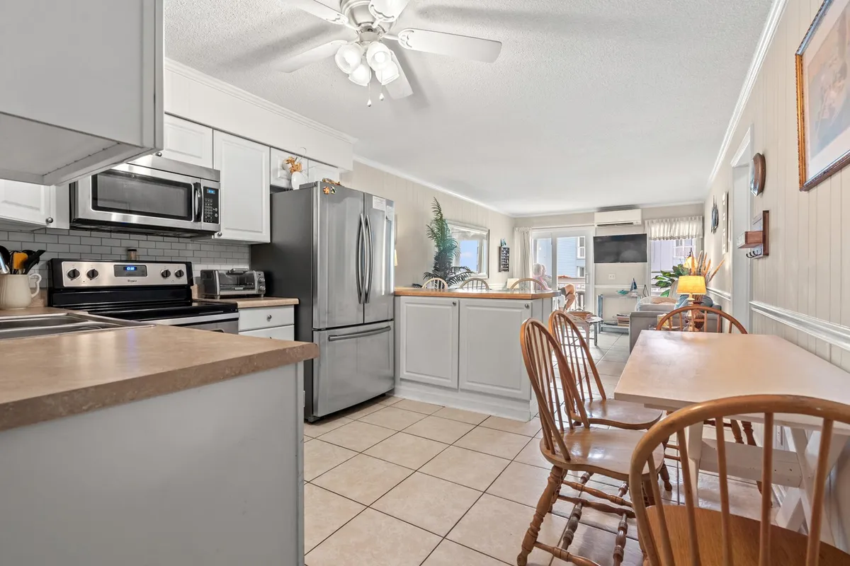 A modern kitchen with a spacious island, stainless steel appliances, and an adjacent dining area. The warm tones and layout invite guests to cook, share meals, and socialize, embodying a welcoming environment for groups or families.